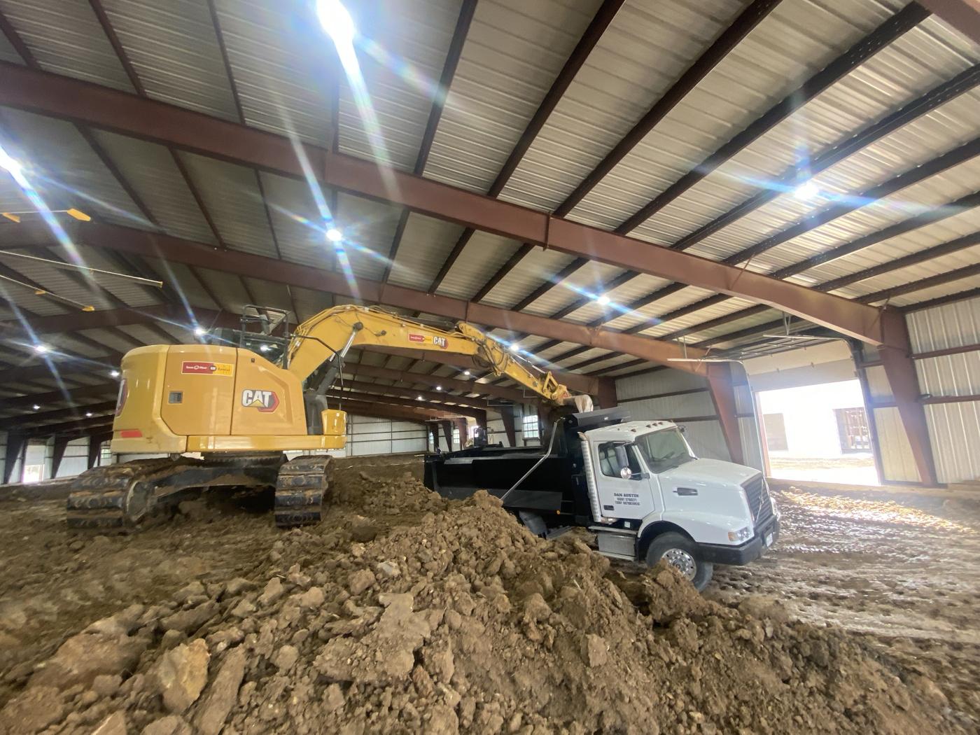 CAT excavator and dump truck inside an arena building